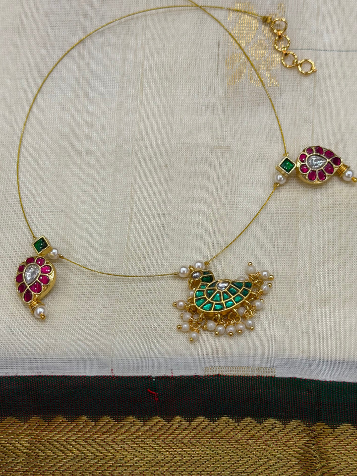 Grace meets tradition in this stunning invisible neckpiece, adorned with Jadau side pendants, a timeless mango motif, and an exquisite peacock centerpiece.