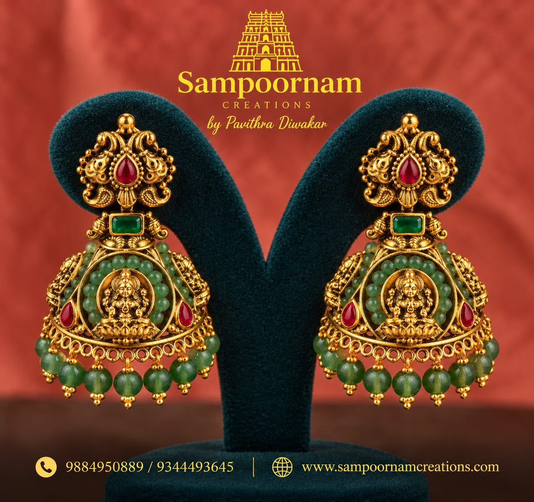 Temple Jewellery inspired Lakshmi Jhumka adorned with vibrant Green beeds and Rich Red Stone accents . Finished with cascading Green Bead hangings for a beautiful , traditional Festive Look .