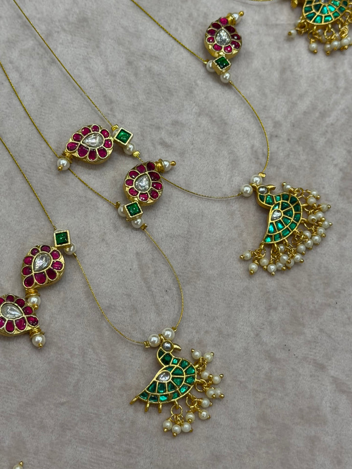 Grace meets tradition in this stunning invisible neckpiece, adorned with Jadau side pendants, a timeless mango motif, and an exquisite peacock centerpiece.