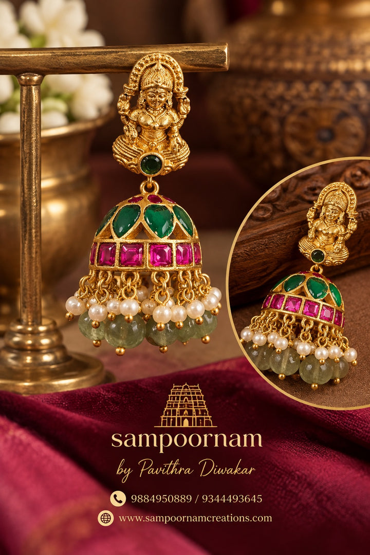 A Stunning Lakshmi motif Jhumka Adorned with Rich Green and Pink stones , delicate Pearl accents and Cascading Green bead Hangings .