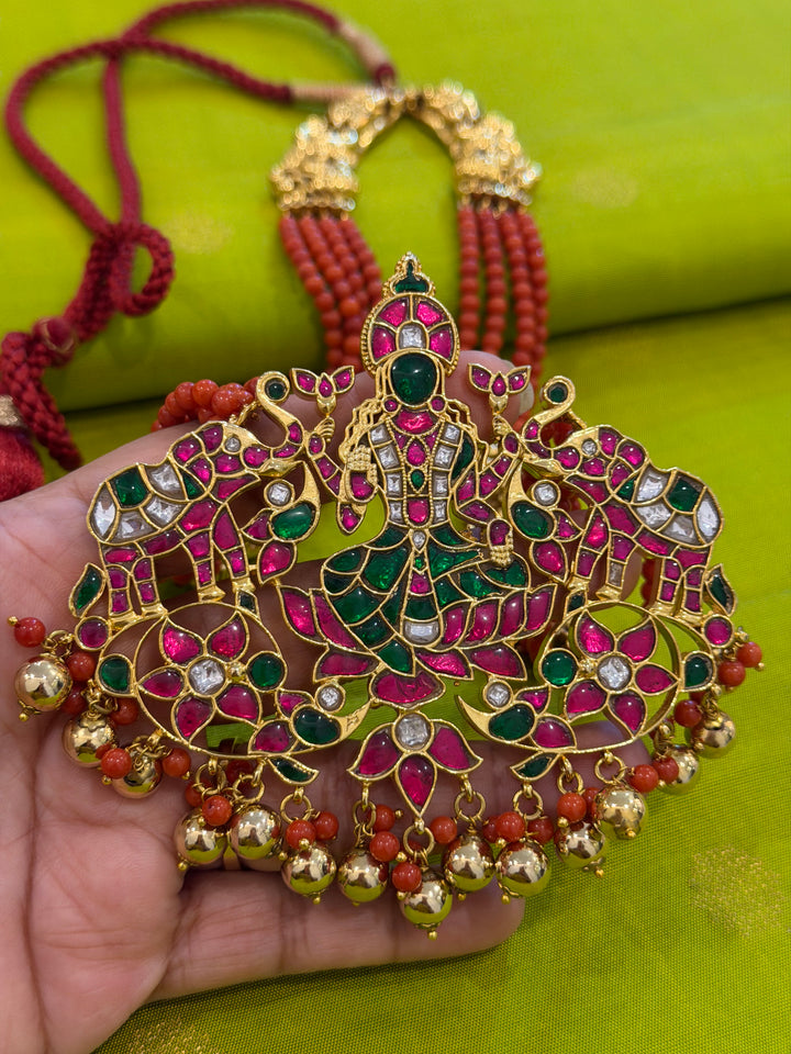 An exquisite Lakshmi pendant necklace featuring handcrafted Kemp stones, coral bead strands, and graceful gold embellishments.