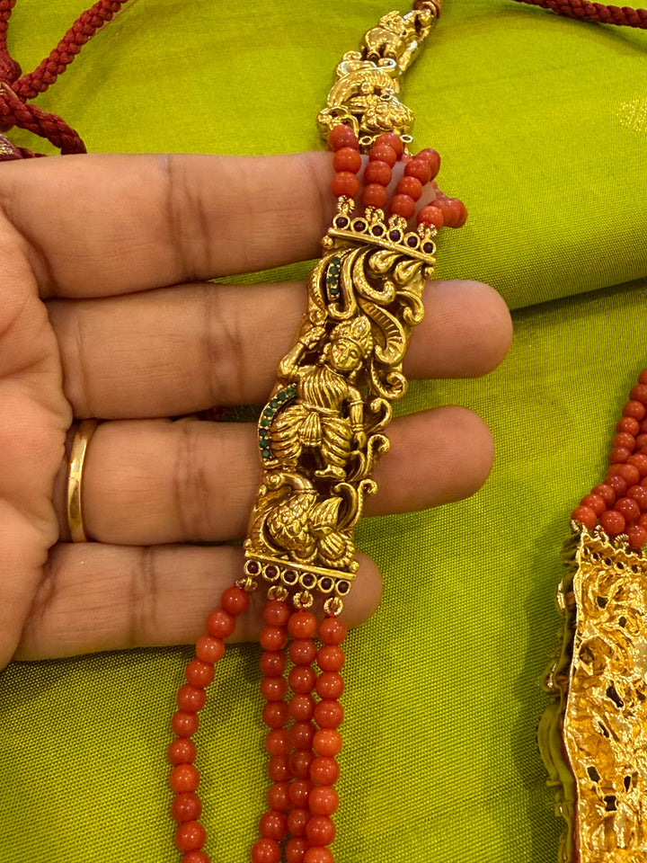 An exquisite Lakshmi pendant necklace featuring handcrafted Kemp stones, coral bead strands, and graceful gold embellishments.