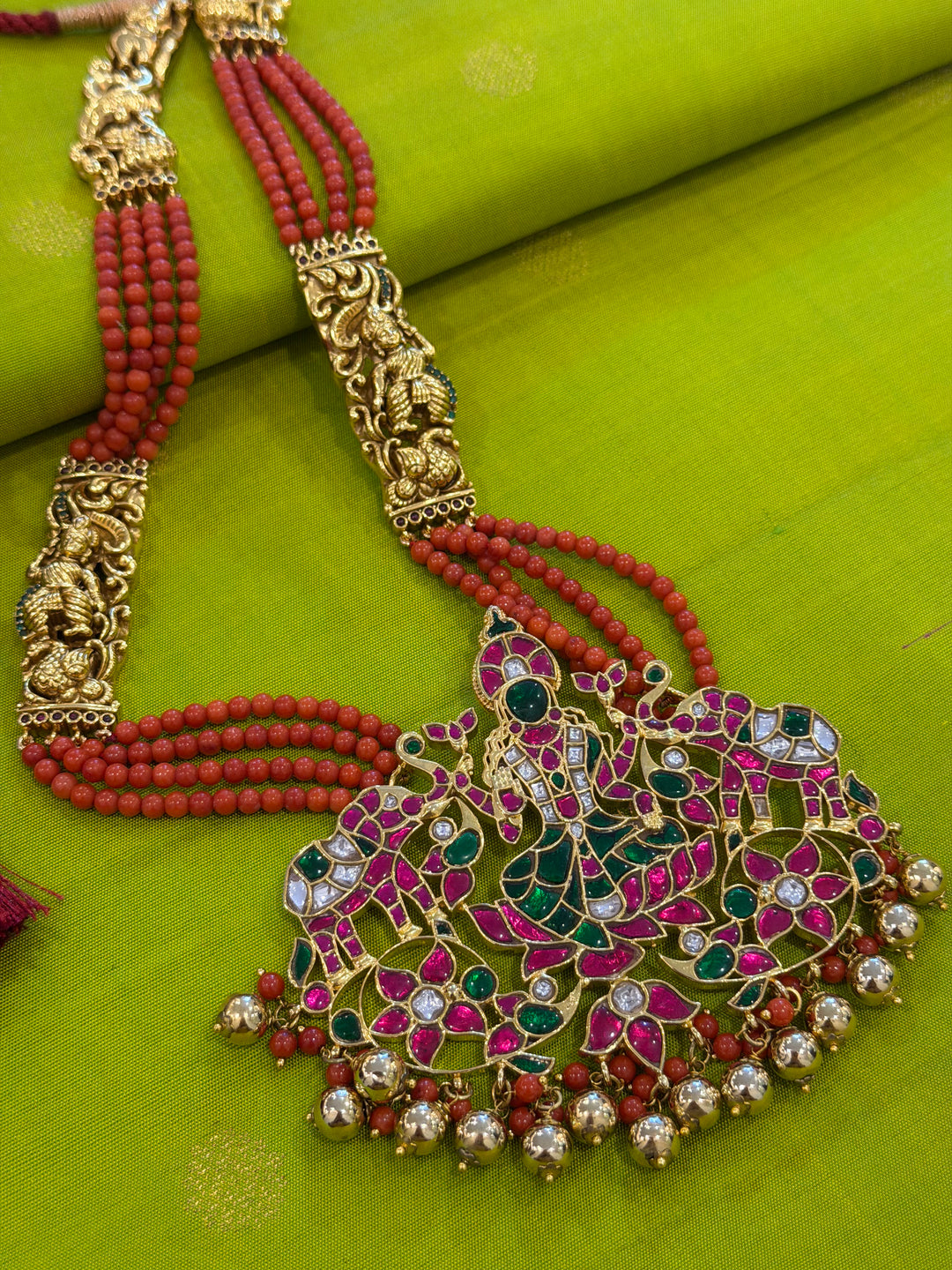 An exquisite Lakshmi pendant necklace featuring handcrafted Kemp stones, coral bead strands, and graceful gold embellishments.