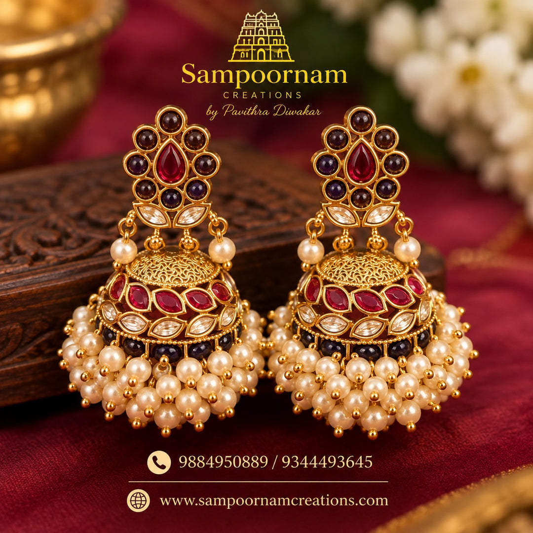 A Statement Floral Jhumka featuring Rich Ruby - Red and Deep Purple Stones and intricate Gold- toned detailing . Finished with a Lavish Cascade of Pearl Hangings and delicate Gold Beads
