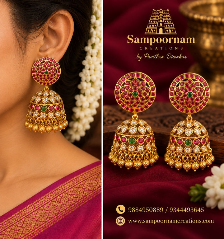 A Statement Kemp - style Jhumka featuring intricate circular floral detailing with Rich Ruby - Pink and Emerald - Green stones , accented with Sparkling white stones . The Beautifully Embellished dome is finished with traditional Gold Ball hangings
