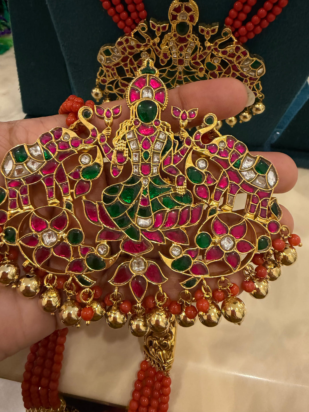 An exquisite Lakshmi pendant necklace featuring handcrafted Kemp stones, coral bead strands, and graceful gold embellishments.