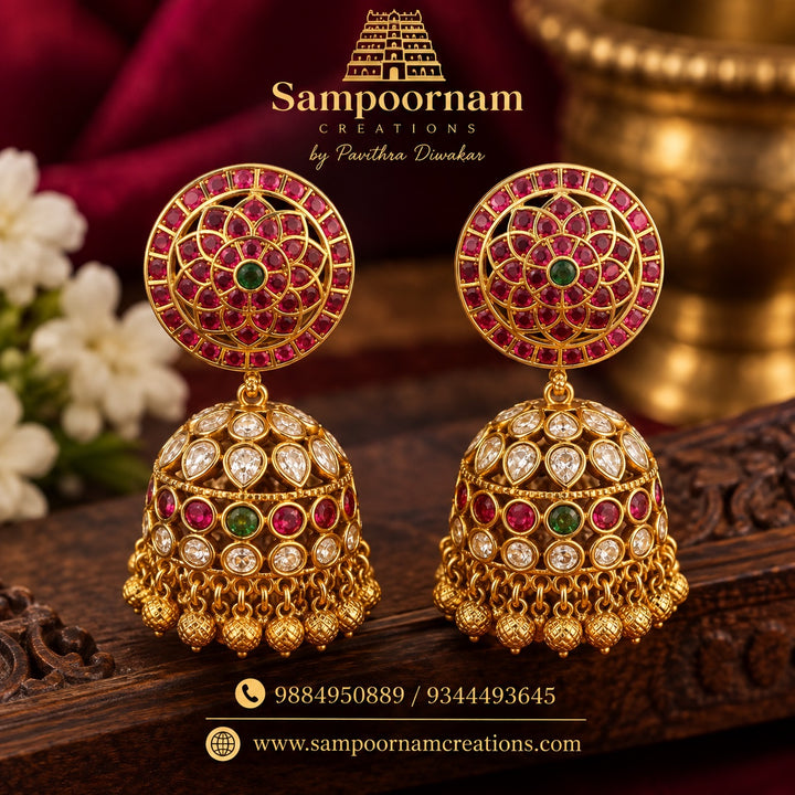 A Statement Kemp - style Jhumka featuring intricate circular floral detailing with Rich Ruby - Pink and Emerald - Green stones , accented with Sparkling white stones . The Beautifully Embellished dome is finished with traditional Gold Ball hangings