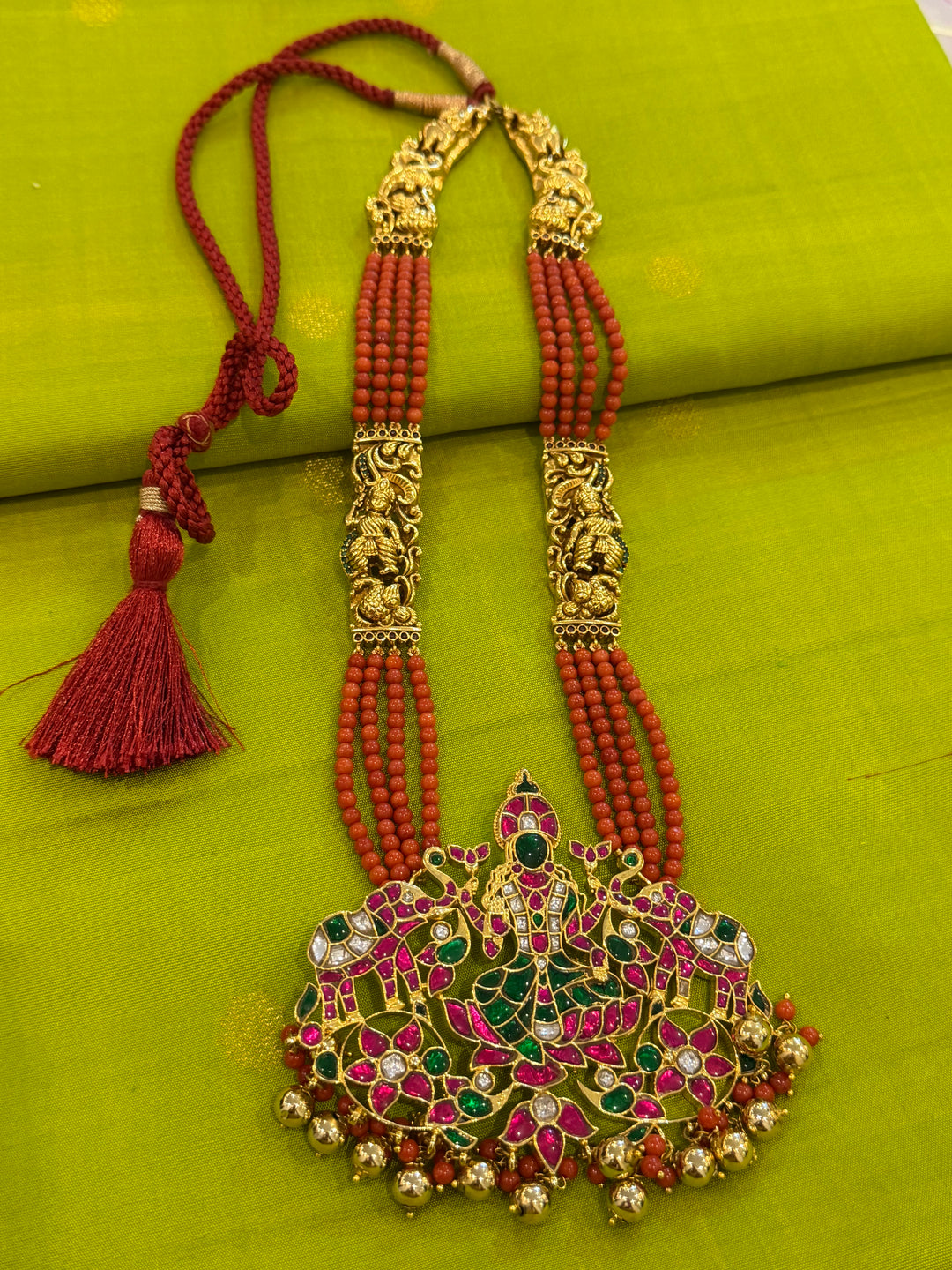 An exquisite Lakshmi pendant necklace featuring handcrafted Kemp stones, coral bead strands, and graceful gold embellishments.