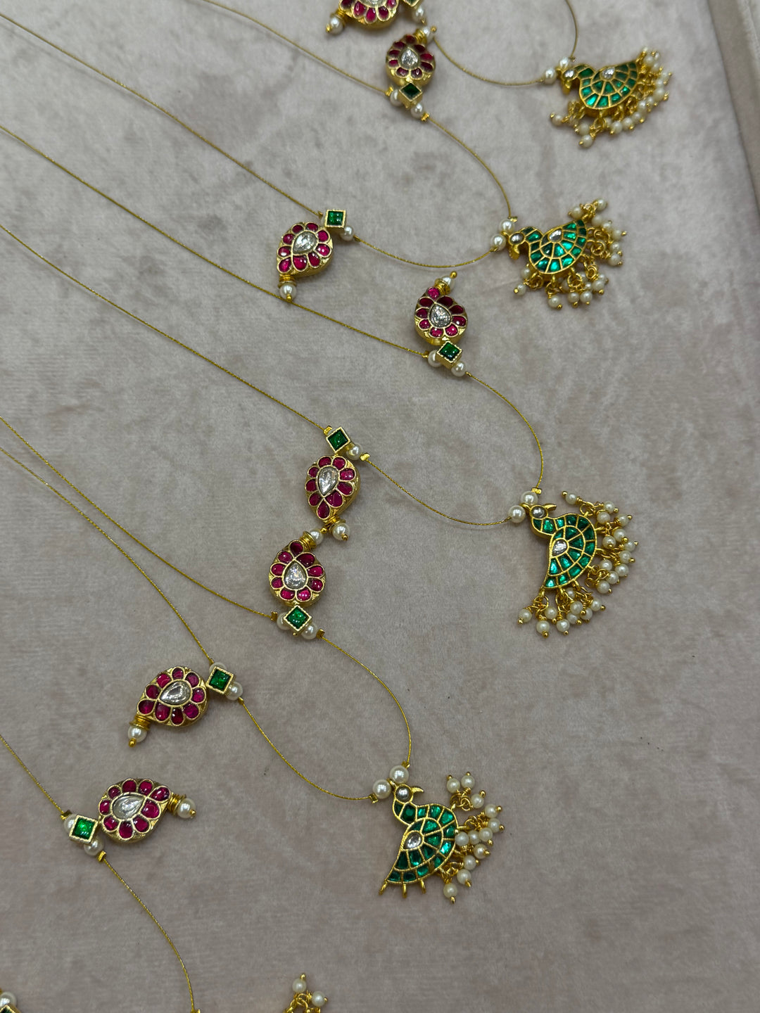 Grace meets tradition in this stunning invisible neckpiece, adorned with Jadau side pendants, a timeless mango motif, and an exquisite peacock centerpiece.