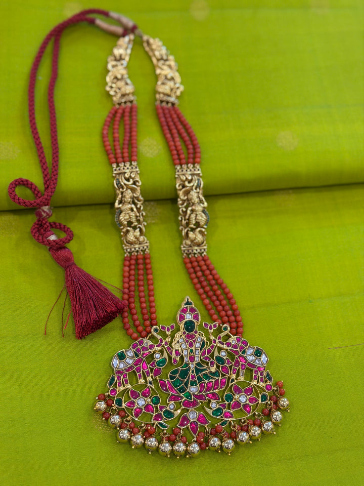 An exquisite Lakshmi pendant necklace featuring handcrafted Kemp stones, coral bead strands, and graceful gold embellishments.