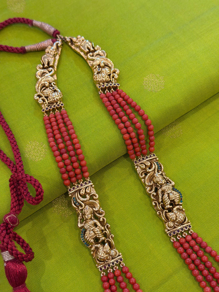 An exquisite Lakshmi pendant necklace featuring handcrafted Kemp stones, coral bead strands, and graceful gold embellishments.