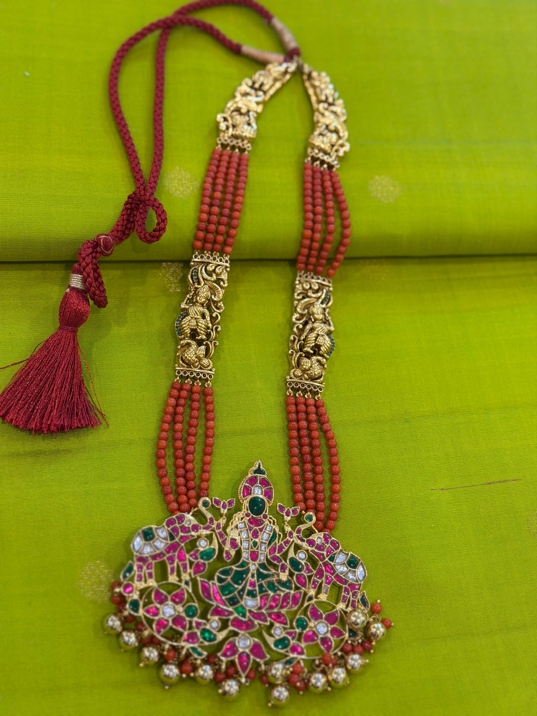 An exquisite Lakshmi pendant necklace featuring handcrafted Kemp stones, coral bead strands, and graceful gold embellishments.
