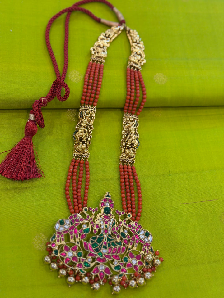 An exquisite Lakshmi pendant necklace featuring handcrafted Kemp stones, coral bead strands, and graceful gold embellishments.