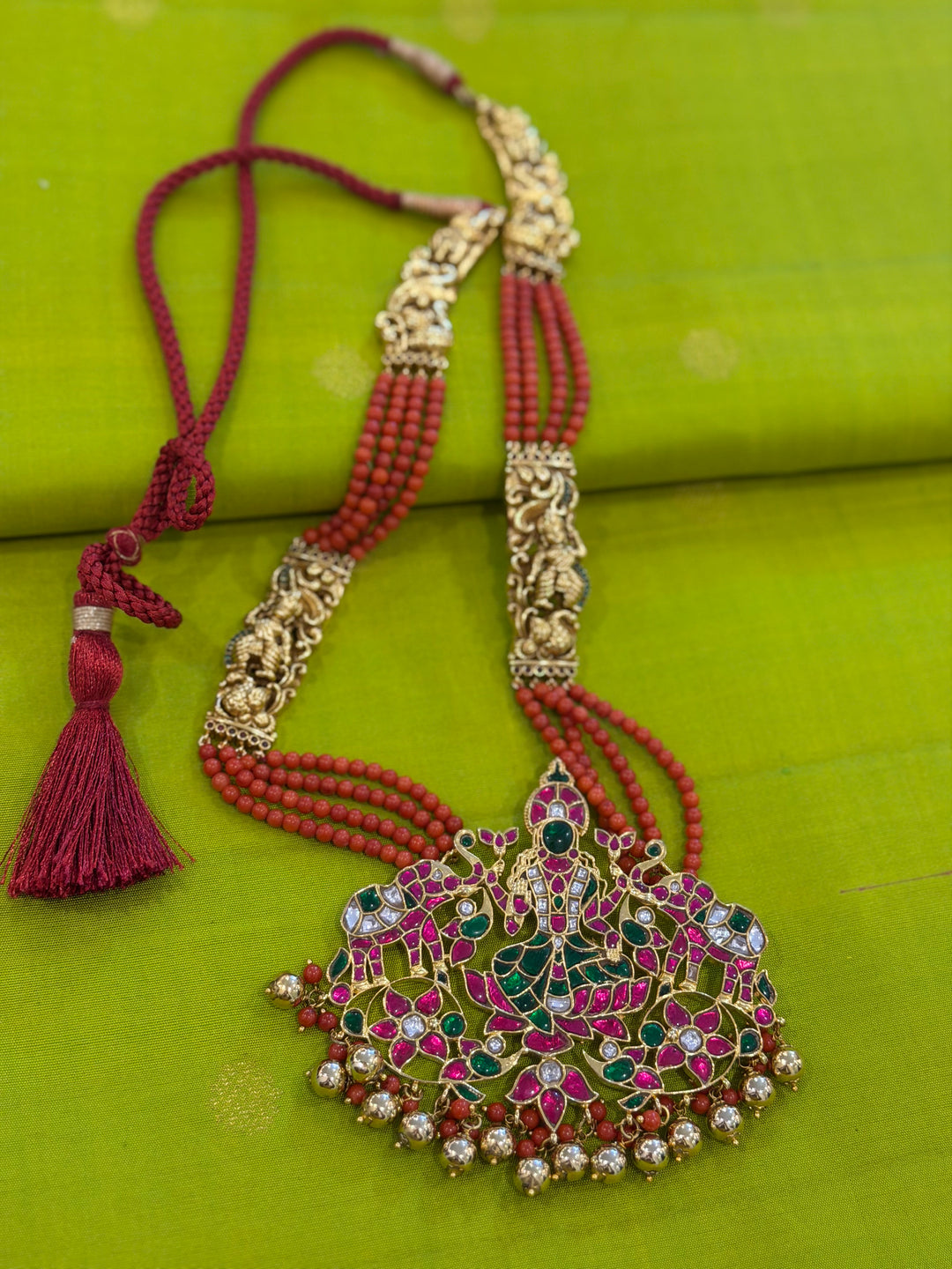 An exquisite Lakshmi pendant necklace featuring handcrafted Kemp stones, coral bead strands, and graceful gold embellishments.