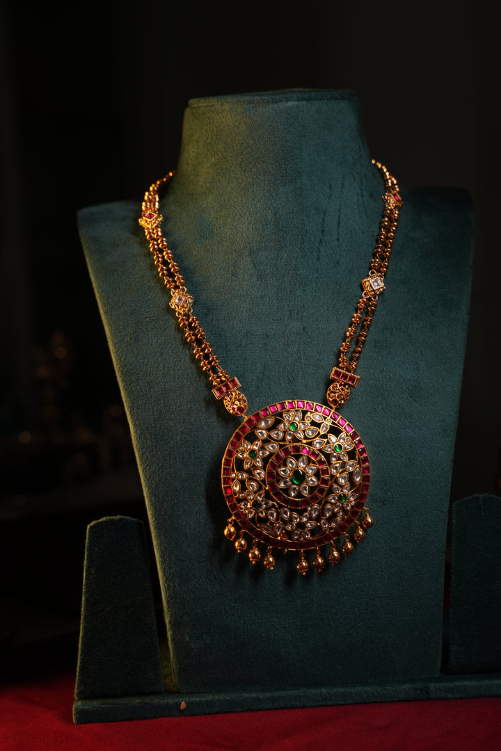 A Heritage Rakudi pendant with gold ball drops adorned with Jadau stones in white, green and red paired with a stone studded rettavari chain