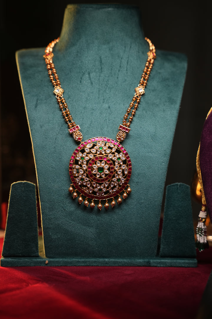 A Heritage Rakudi pendant with gold ball drops adorned with Jadau stones in white, green and red paired with a stone studded rettavari chain