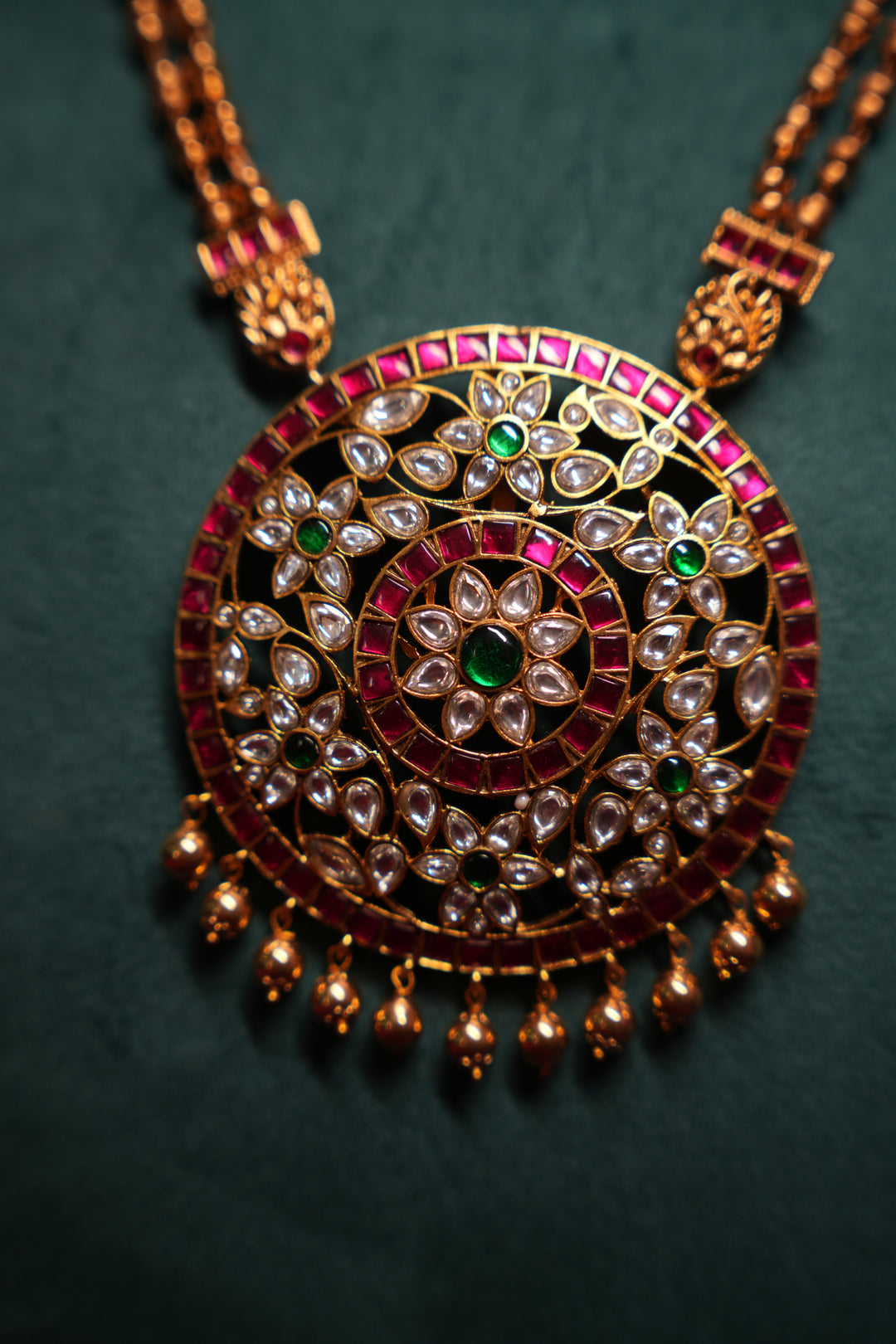 A Heritage Rakudi pendant with gold ball drops adorned with Jadau stones in white, green and red paired with a stone studded rettavari chain