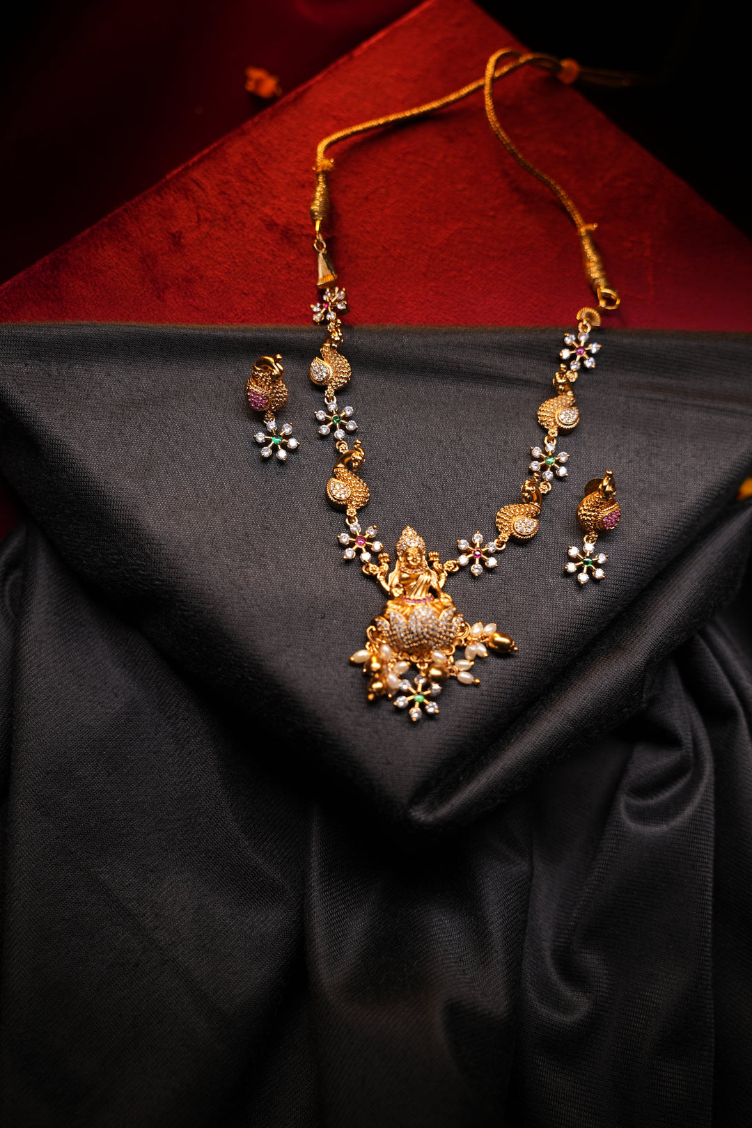 Divine Elegance , A traditional Necklace with a Mahalakshmi Pendant in red green and white stones with peacock detailing
