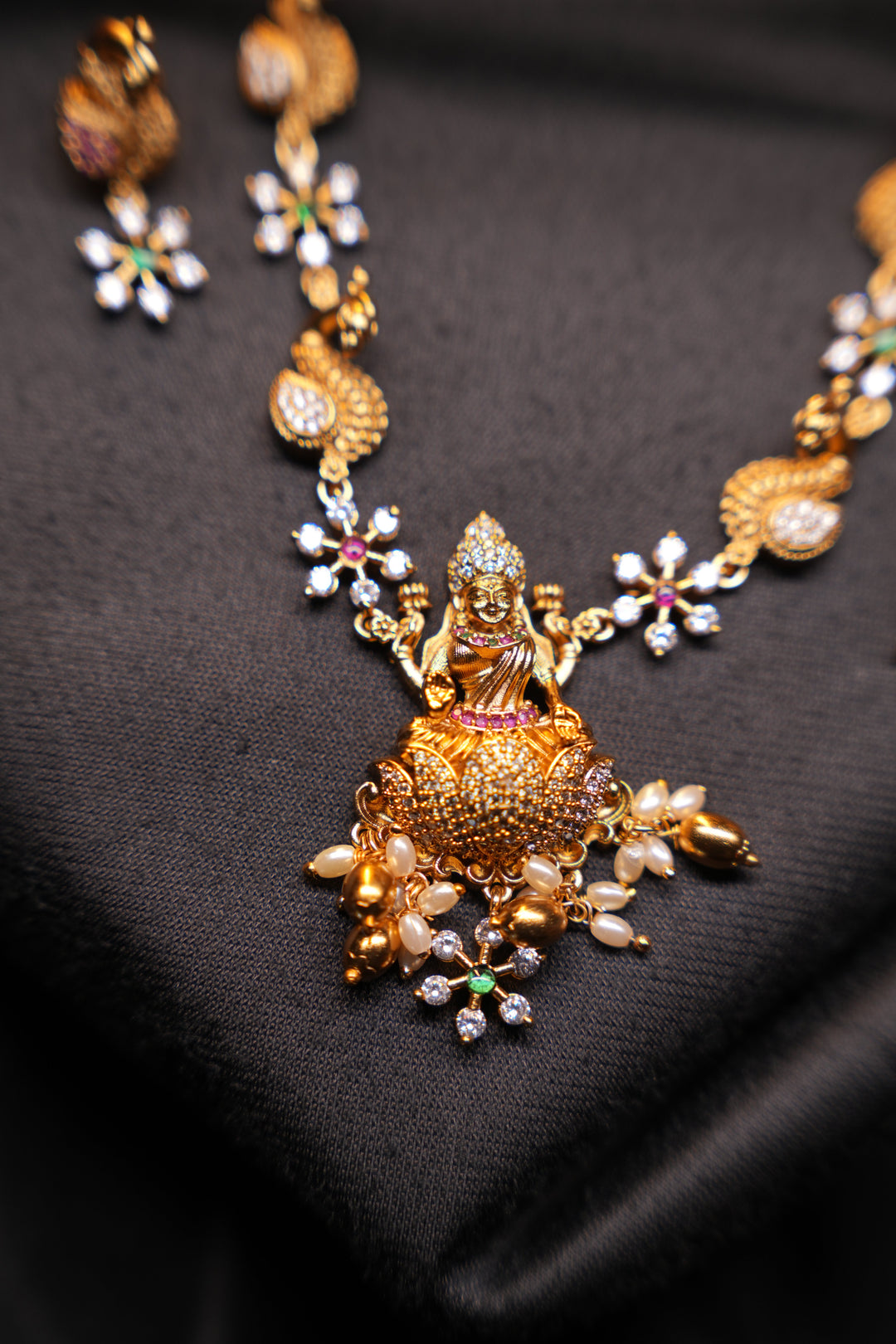 Divine Elegance , A traditional Necklace with a Mahalakshmi Pendant in red green and white stones with peacock detailing
