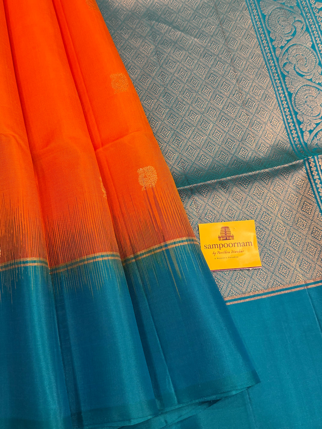 Fanta Orange with Turquoise Blue, rich zari butta in the body and an elaborate rich Pallu Pure Soft Silk Saree