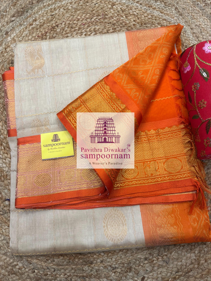 Offwhite with Orange , rich Zari checks in the body , Mayil and Chakram rich butta in the body , traditional borders and rich Pallu Silk Cotton Saree