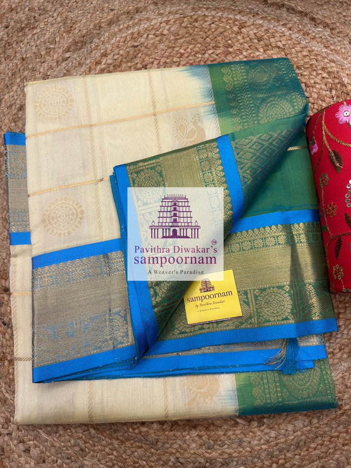 Offwhite  with Blue  , rich Zari checks in the body , Mayil and Chakram rich butta in the body , traditional borders and rich Pallu Silk Cotton Saree