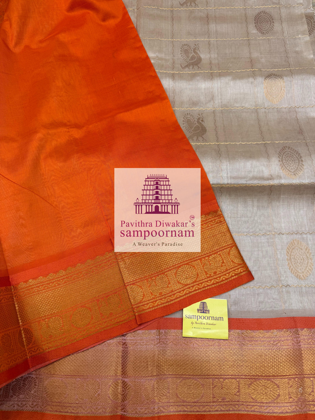 Offwhite with Orange , rich Zari checks in the body , Mayil and Chakram rich butta in the body , traditional borders and rich Pallu Silk Cotton Saree
