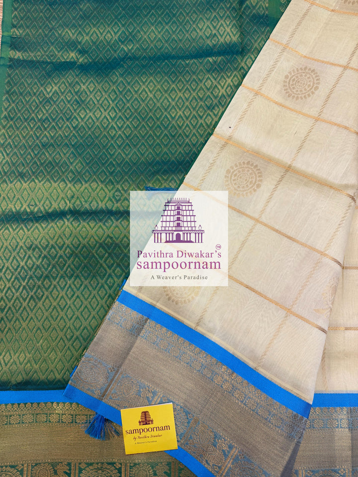 Offwhite  with Blue  , rich Zari checks in the body , Mayil and Chakram rich butta in the body , traditional borders and rich Pallu Silk Cotton Saree