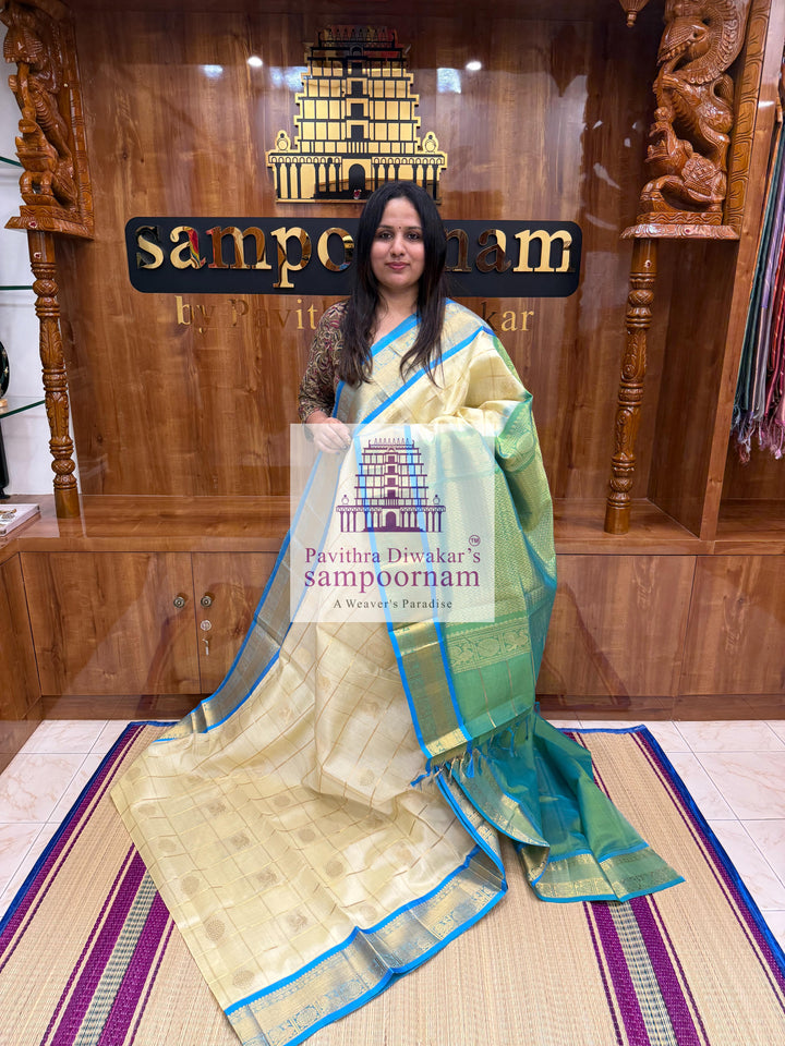 Offwhite  with Blue  , rich Zari checks in the body , Mayil and Chakram rich butta in the body , traditional borders and rich Pallu Silk Cotton Saree