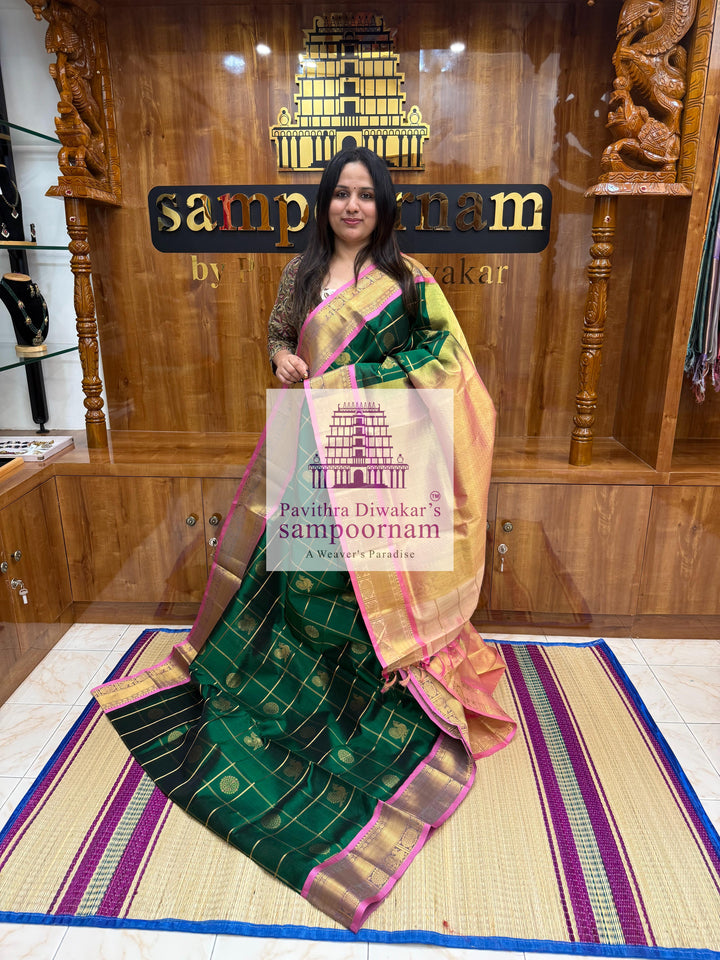 Bottle Green with Peachish Pink , Baby Pink Selvedge  , rich Zari checks in the body , Mayil and Chakram rich butta in the body , traditional borders and rich Pallu Silk Cotton Saree