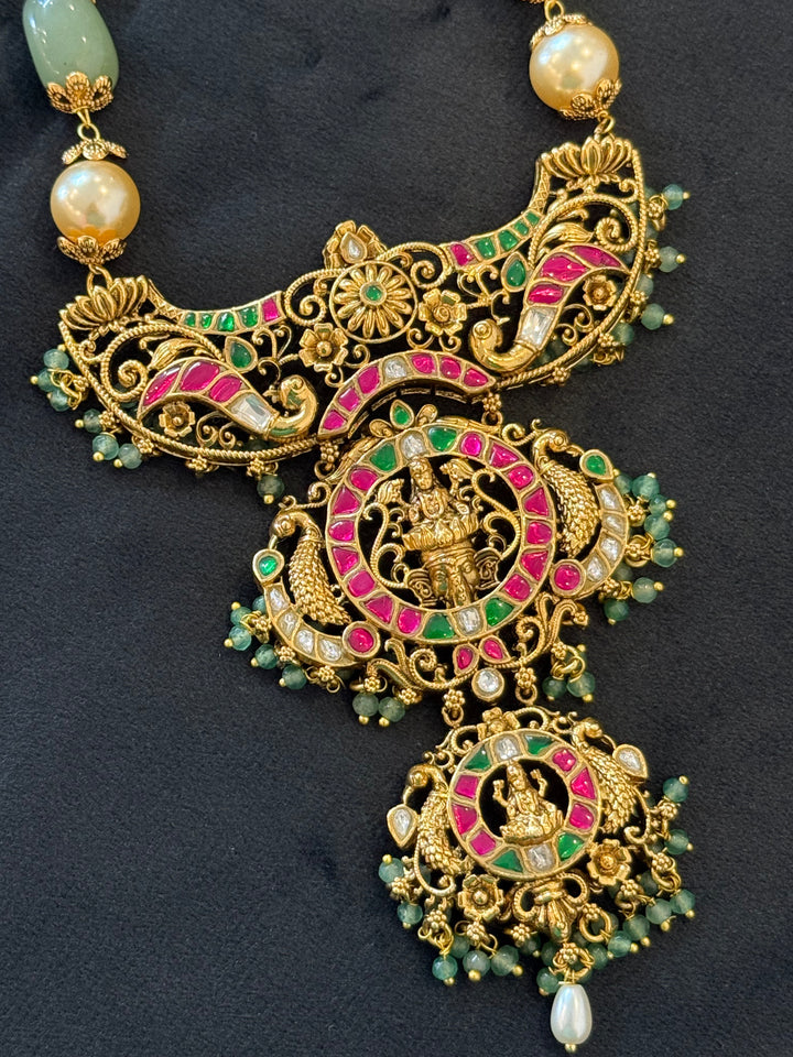 A regal pearl, gold, and emerald beaded necklace, completed with a magnificent three-layered Jadau pendant depicting Goddess Saraswati and Lord Ganesha. A classic pendant that elevates any traditional look.( Without Jhumka )