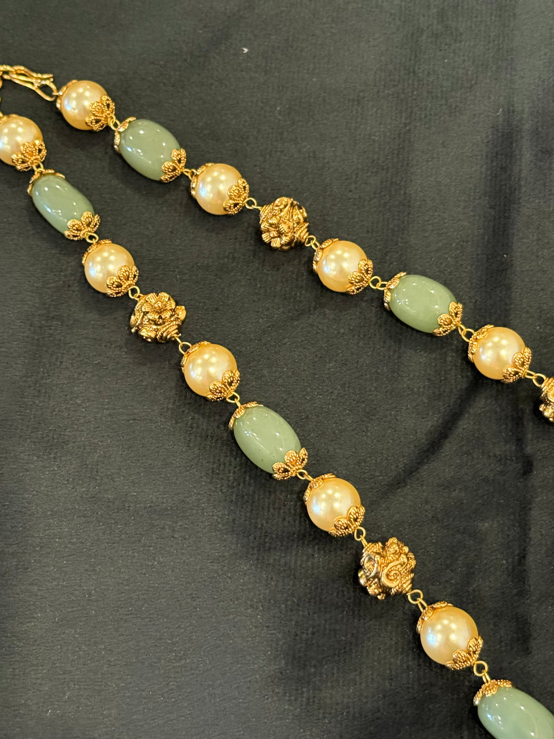 A regal pearl, gold, and emerald beaded necklace, completed with a magnificent three-layered Jadau pendant depicting Goddess Saraswati and Lord Ganesha. A classic pendant that elevates any traditional look.( With Jhumka )