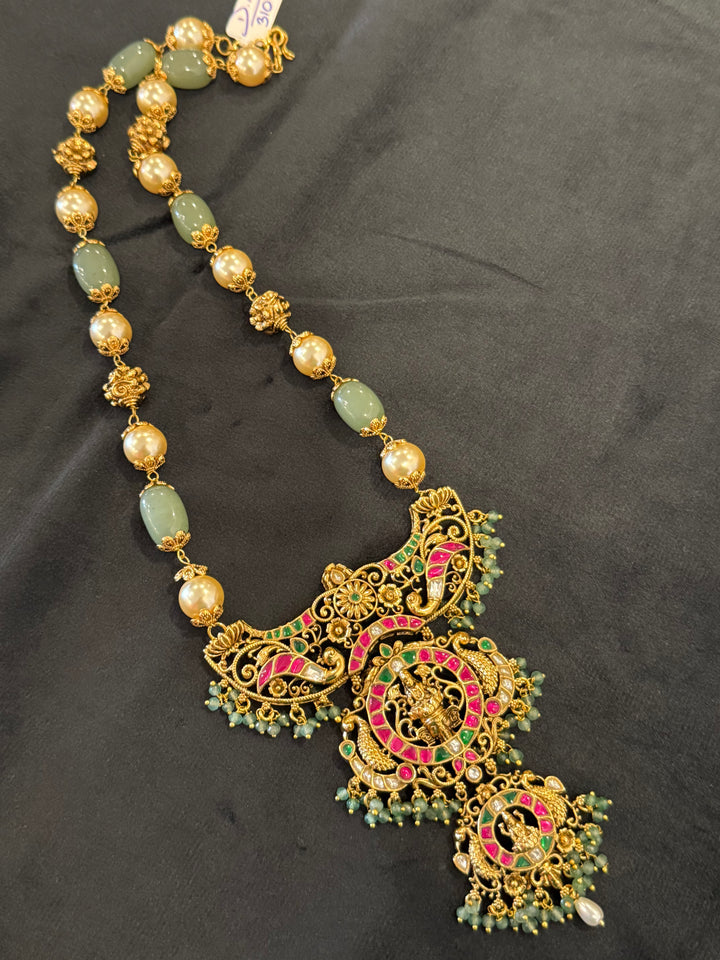 A regal pearl, gold, and emerald beaded necklace, completed with a magnificent three-layered Jadau pendant depicting Goddess Saraswati and Lord Ganesha. A classic pendant that elevates any traditional look.( With Jhumka )