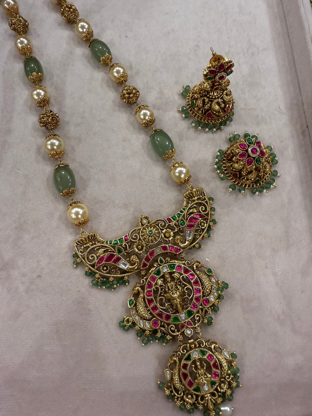 A regal pearl, gold, and emerald beaded necklace, completed with a magnificent three-layered Jadau pendant depicting Goddess Saraswati and Lord Ganesha. A classic pendant that elevates any traditional look.( Without Jhumka )
