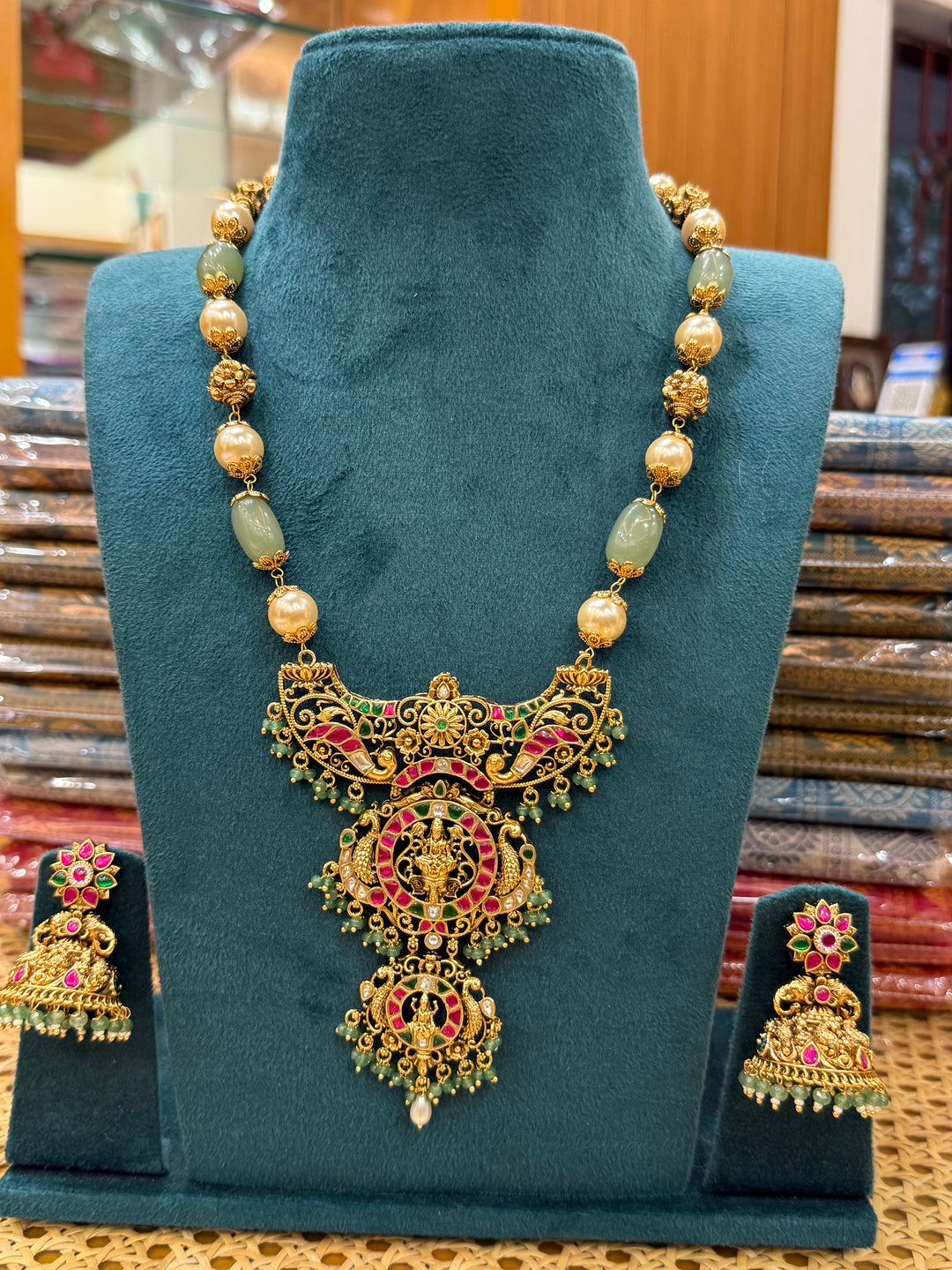 A regal pearl, gold, and emerald beaded necklace, completed with a magnificent three-layered Jadau pendant depicting Goddess Saraswati and Lord Ganesha. A classic pendant that elevates any traditional look.( Without Jhumka )