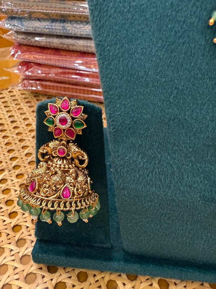 A regal pearl, gold, and emerald beaded necklace, completed with a magnificent three-layered Jadau pendant depicting Goddess Saraswati and Lord Ganesha. A classic pendant that elevates any traditional look.( With Jhumka )