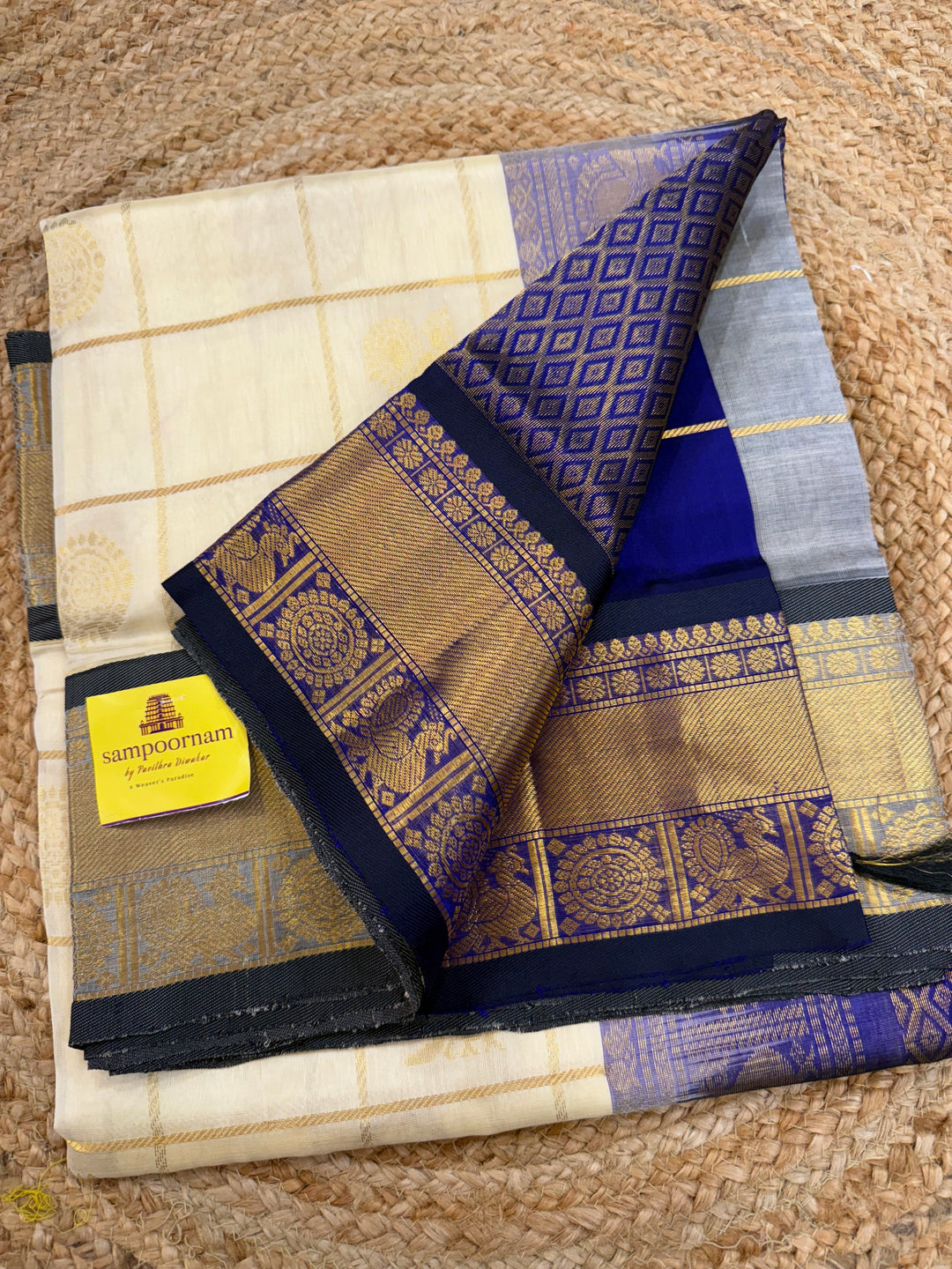 Offwhite with Dark Blue colour ,checks in the body with Mayil Chakram butta , traditional border and rich Pallu Silk Cotton Saree
