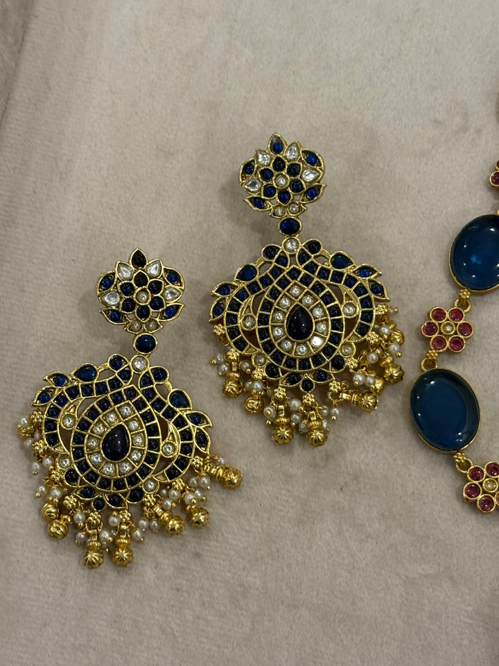Our vintage blue pendant set, with rich blue & white kemp stones. The chain features blue stones and floral designs embellished with red and white stones. Paired with beautifully designed hanging earrings adorned with pearls and gold beads.