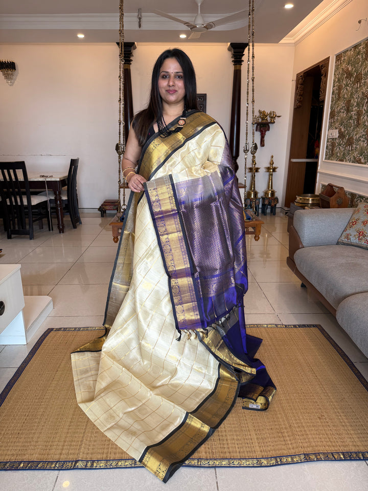 Offwhite with Dark Blue colour ,checks in the body with Mayil Chakram butta , traditional border and rich Pallu Silk Cotton Saree