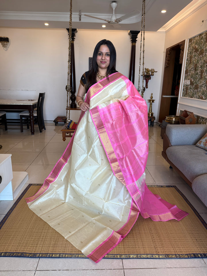 OffWhite with Baby Pink , rich zari butta in the body , traditional borders and rich Pallu Korvai Silk Cotton Saree