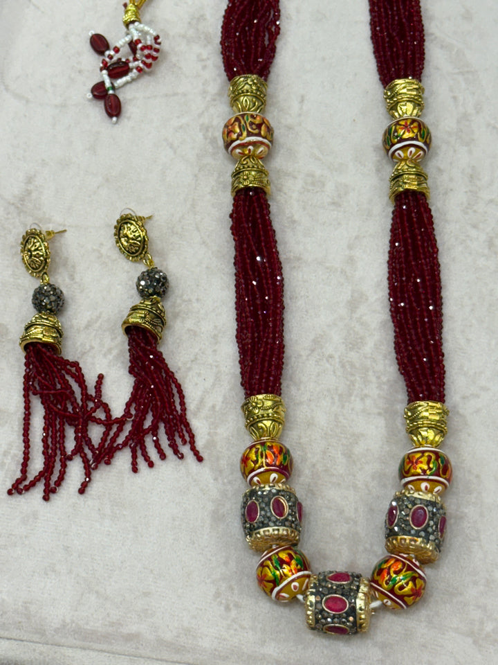Dark Red multi crystal bead stranded neckpiece adorned with antique gold elements and intricate meenakari balls, paired with tassel shaped eardrops
