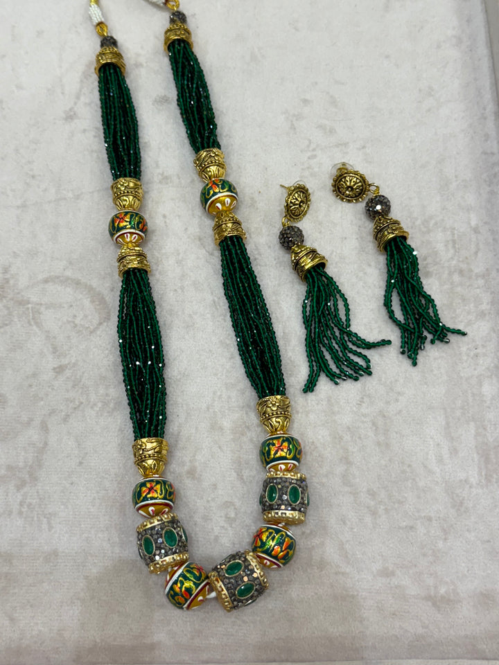 Dark Green multi crystal bead stranded neckpiece adorned with antique gold elements and intricate meenakari balls, paired with tassel shaped ear drops