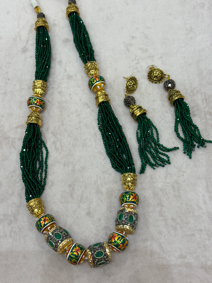 Dark Green multi crystal bead stranded neckpiece adorned with antique gold elements and intricate meenakari balls, paired with tassel shaped ear drops