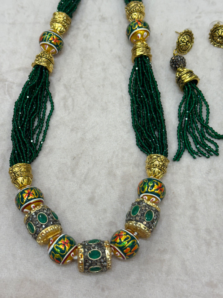 Dark Green multi crystal bead stranded neckpiece adorned with antique gold elements and intricate meenakari balls, paired with tassel shaped ear drops