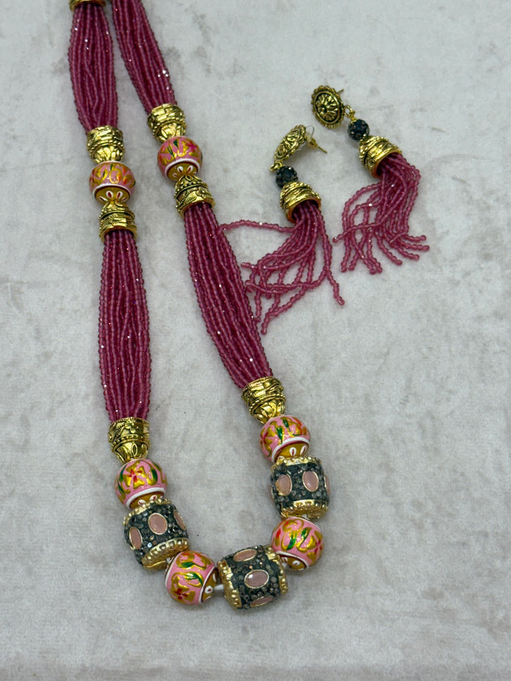 Pink multi crystal bead stranded neckpiece adorned with antique gold elements and intricate meenakari balls, paired with tassel shaped ear drops.