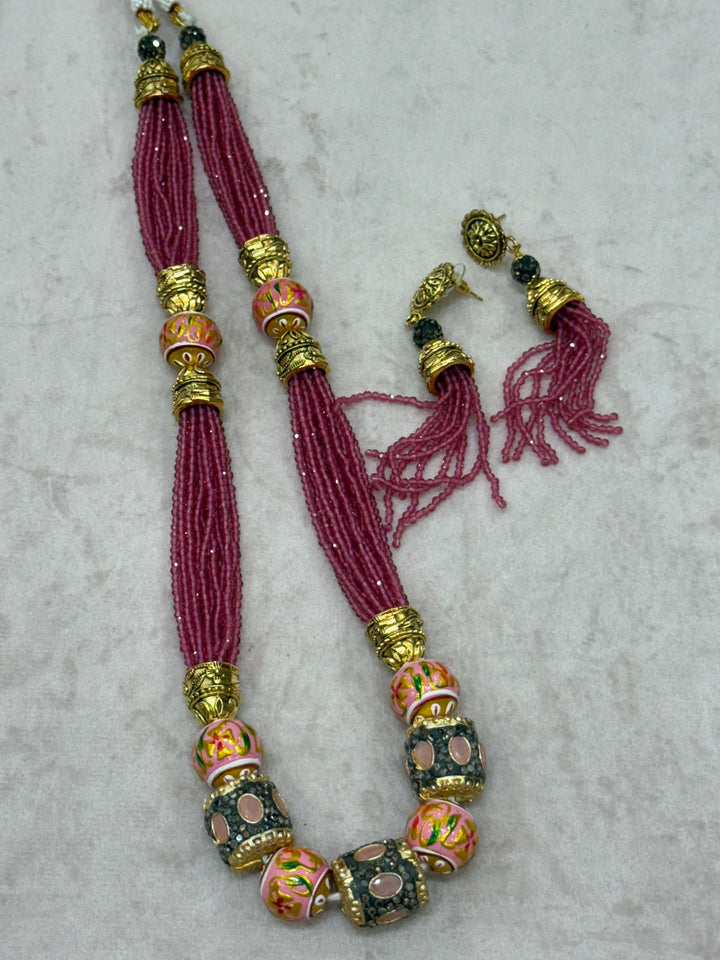Pink multi crystal bead stranded neckpiece adorned with antique gold elements and intricate meenakari balls, paired with tassel shaped ear drops.