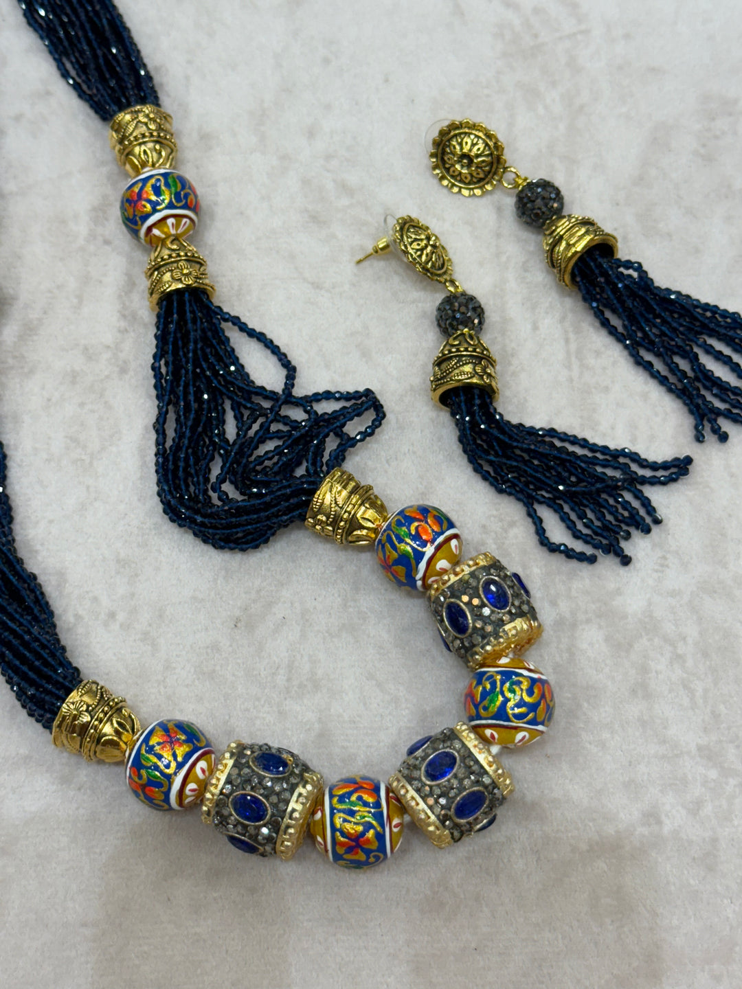 Dark Blue multi crystal bead stranded neckpiece adorned with antique gold elements and intricate meenakari balls, paired with tassel shaped eardrops