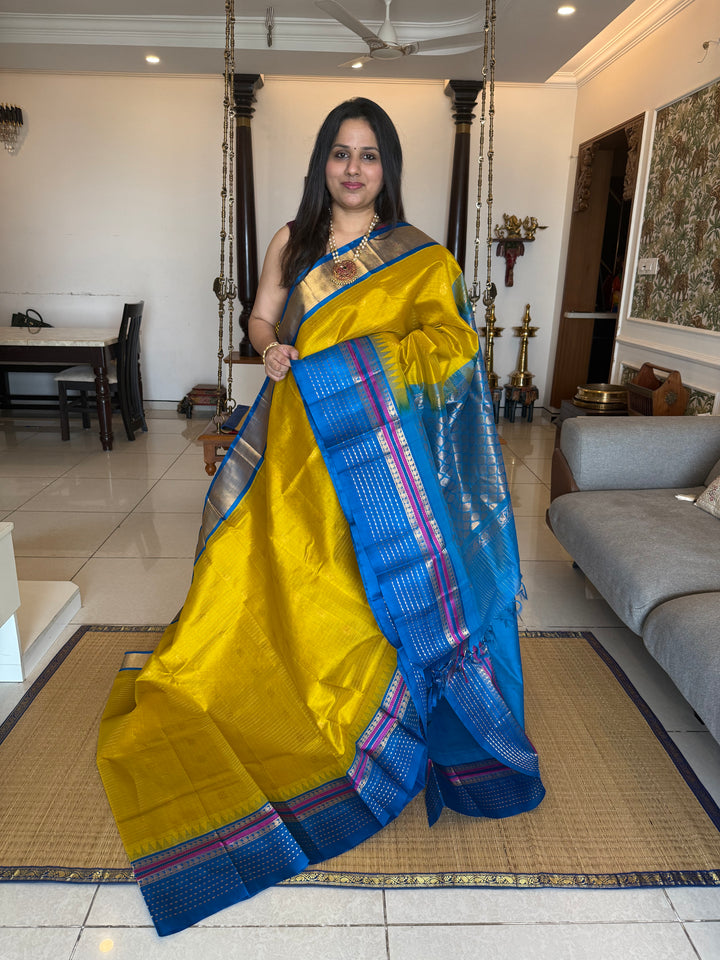 Yellow with Copper Sulphate Blue one side big border with Lakshadeepam butta , Zari butta in the body with Zari checks and grand Pallu Korvai Silk Cotton Saree