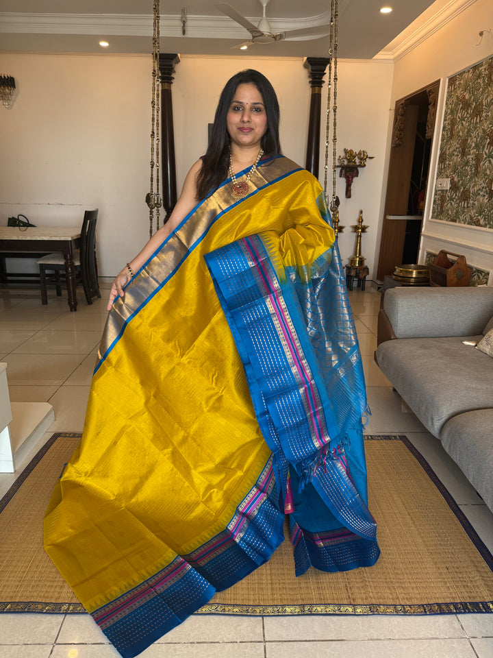 Yellow with Copper Sulphate Blue one side big border with Lakshadeepam butta , Zari butta in the body with Zari checks and grand Pallu Korvai Silk Cotton Saree