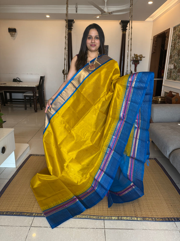 Yellow with Copper Sulphate Blue one side big border with Lakshadeepam butta , Zari butta in the body with Zari checks and grand Pallu Korvai Silk Cotton Saree